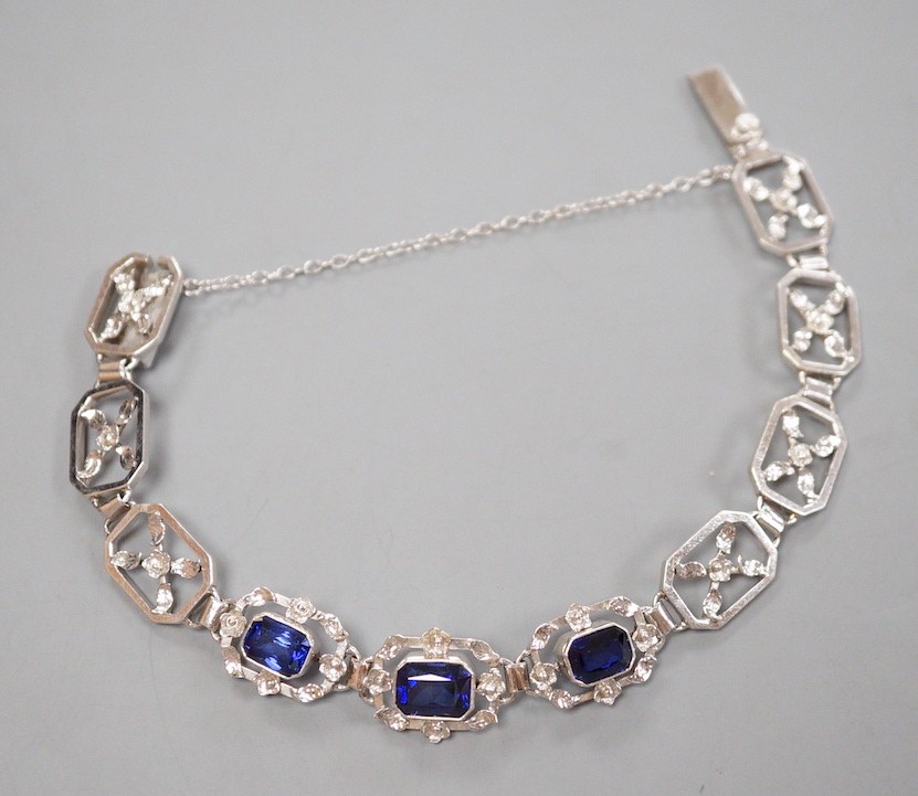 A modern 9ct white metal and three stone emerald cut synthetic sapphire set pierced link bracelet, approx. 18cm, gross weight 16.7 grams.